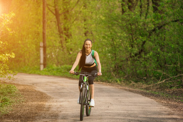 Naklejka premium Active life. Sport girl trailing on a bike enjoys the view of sunset over an forest. Heathy lifestyle concept. Text placement