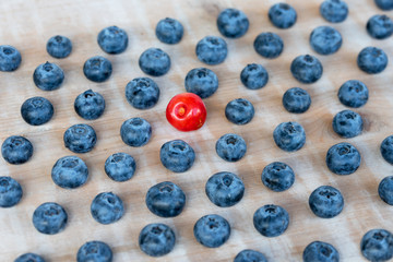 eine rote Kirsche inmitten von Blaubeeren, verteilt auf einem Holz Hintergrund