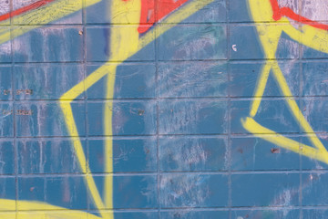 Yellow graffiti details on blue tiles wall