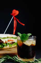 big sandwich for couple in love on black background rosemary cucumber wooden board Street food, fast food. Homemade burgers with beef, cheese  on the wooden table. Glass of cola with ice, mint