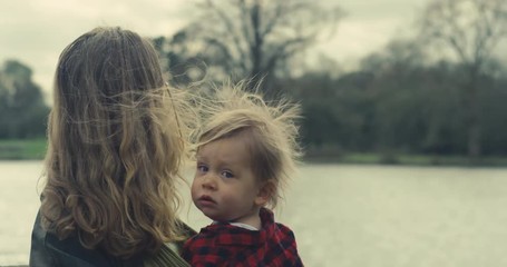 Mother standing in forest by lake with toddler