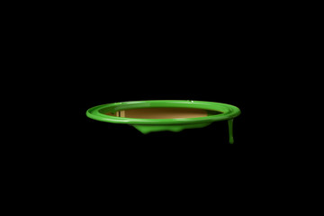 Green oil paint leaking over the wall of empty metal bucket