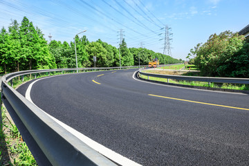 Curved asphalt highway and green forest on a sunny day