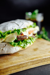 big sandwich  on black background rosemary cucumber wooden board Street food, fast food. Homemade burgers with beef, cheese  on the wooden table. Glass of cola with ice, mint