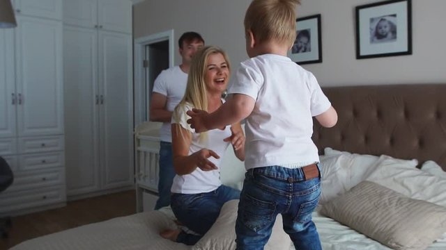 Parents having fun with their little daughter on bed. Family spending time at the morning