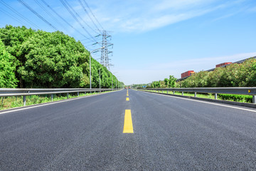 Straight asphalt highway and green forest on a sunny day