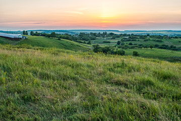 Fototapeta na wymiar sunset behind a green field and village
