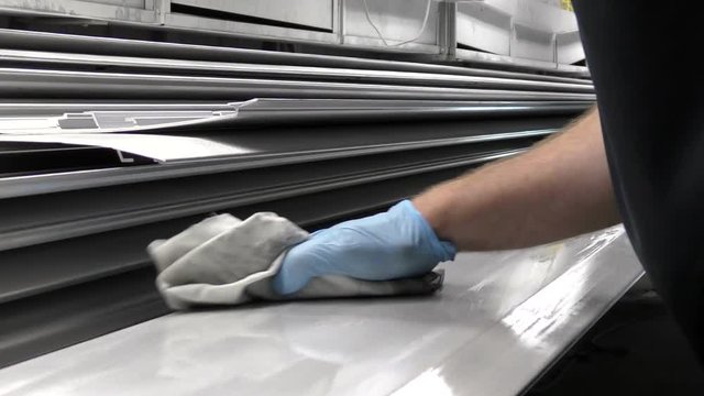 man cleaning a metal panel with a cloth preparing for spraying