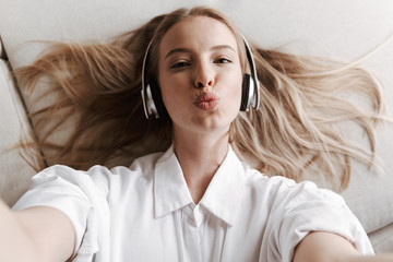Pretty young woman indoors at home listening music