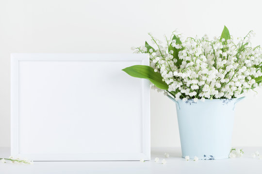 Mockup of picture frame decorated flowers in vase on white background with clean space for text.
