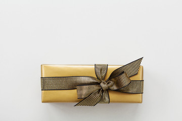 Gift or present box decorated gold ribbon on table top view. Flat lay composition for Christmas or birthday.