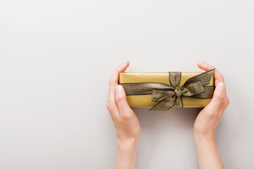 Woman hands with golden present or gift box top view. Flat lay composition for birthday or...