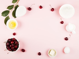 Ingredients for cherry pie - milk, butter, eggs, flour, cherry, sugar on a pink background. Top view, copy space. Food background