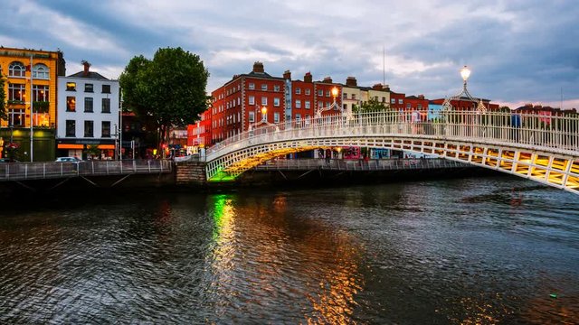 Dublin, Ireland. Night view of famous illuminated Ha Penny Bridge in Dublin, Ireland. Time-lapse at sunset. Light to dark, zoom in
