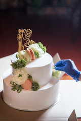 A hand decorating wedding cake