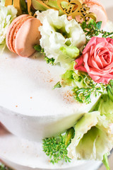 Tasty white cake decorated with flowers and macaroons