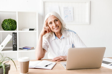 Happy mature woman using laptop computer.