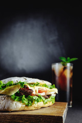 big sandwich for couple on black background rosemary cucumber wooden board Street food, fast food. Homemade burgers with beef, cheese  on the wooden table. Glass of cola with ice, mint