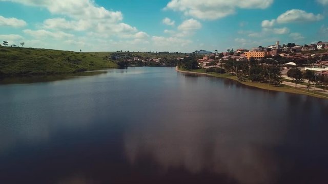 Incredible aerial flying over a beautiful blue lake next to a small village on a sunny day