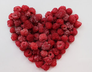 one ripe red heart-shaped raspberry over white backgroung