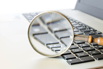 Old magnifying glass on the laptop keyboard. The concept of information search on the Internet