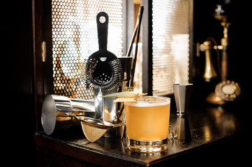 Yellow cocktail and set of different barman equipment on the sill
