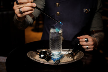 Bartender decorate glass with a transparent blue caramel sheet