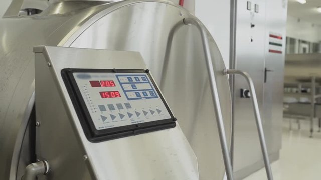 Milk factory modern equipment. Big steel pasteurization tank with control panel with blue and grey buttons on it