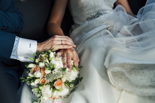 Bride and groom hands with bridal bouquet