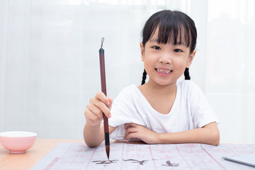 Asian little Chinese girl practice Chinese calligraphy