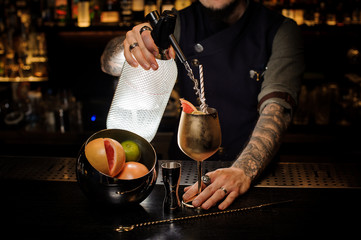 Professional bartender adding drink from the syphon to the cocktail copper cup