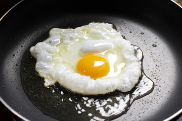 Fried sunny side up egg in a hot pan.