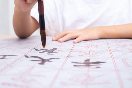 Close up of children hands holding brush to practice Chinese calligraphy