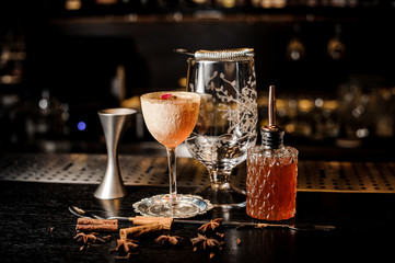 Fresh orange cocktail with rose petal on the holder and different bartender equipment