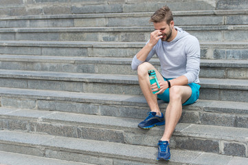 Tired after training on fresh air. Stay hydrated and healthy. Macho with water bottle sit on steps,...