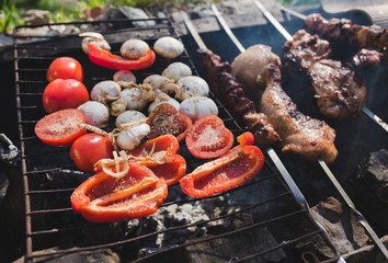 Grilled vegetables, chicken and pork meat on the open fire. Onions, mushrooms, tomatoes and red pepper on the grill grate. Barbecue place made from bricks. Summer tasty food photo