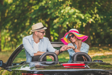 Beautiful couple holding hands in cabriolet car. Summer vacation on the road concepts.