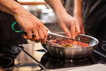 oncept of the correct cooking of meat. The chef prepares, fries a steak of mutton, pork or veal in a frying pan on an induction cooker, with the addition of spices, marinade and wine. Selective focus
