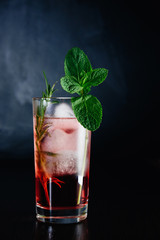 pink cocktail with mint and rosemary on black background close-up