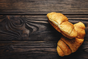 two fresh croissants on dark wooden table place for text