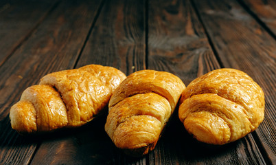 three croissants on dark wooden table place for text