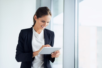 Happy business woman using tablet at corporate office