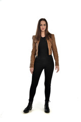 Fototapeta premium full length portrait of brunette girl wearing brown leather jacket. standing pose on white background.