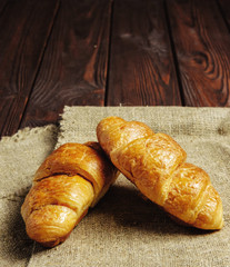 two croissants on rag and wooden table  place for text