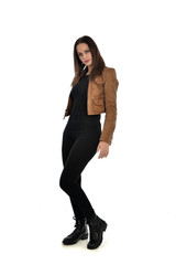 full length portrait of brunette girl wearing brown leather jacket.   standing pose on white...