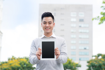 Young Businessman holding and showing the screen of digital tablet