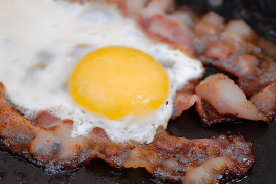 Close up fried eggs with bacon on an old iron pan. Shallow depth of field.