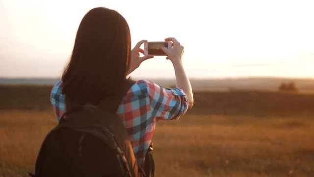 Hipster hiker silhouette girl is shooting video of beautiful nature sundown on cell telephone smartphone slow motion video. Female tourist is taking photo with mobile phone camera. girl tourist travel
