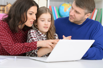 parents and daughter using laptop
