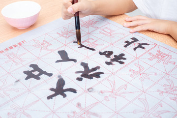 Close up of children hands holding brush to practice Chinese calligraphy